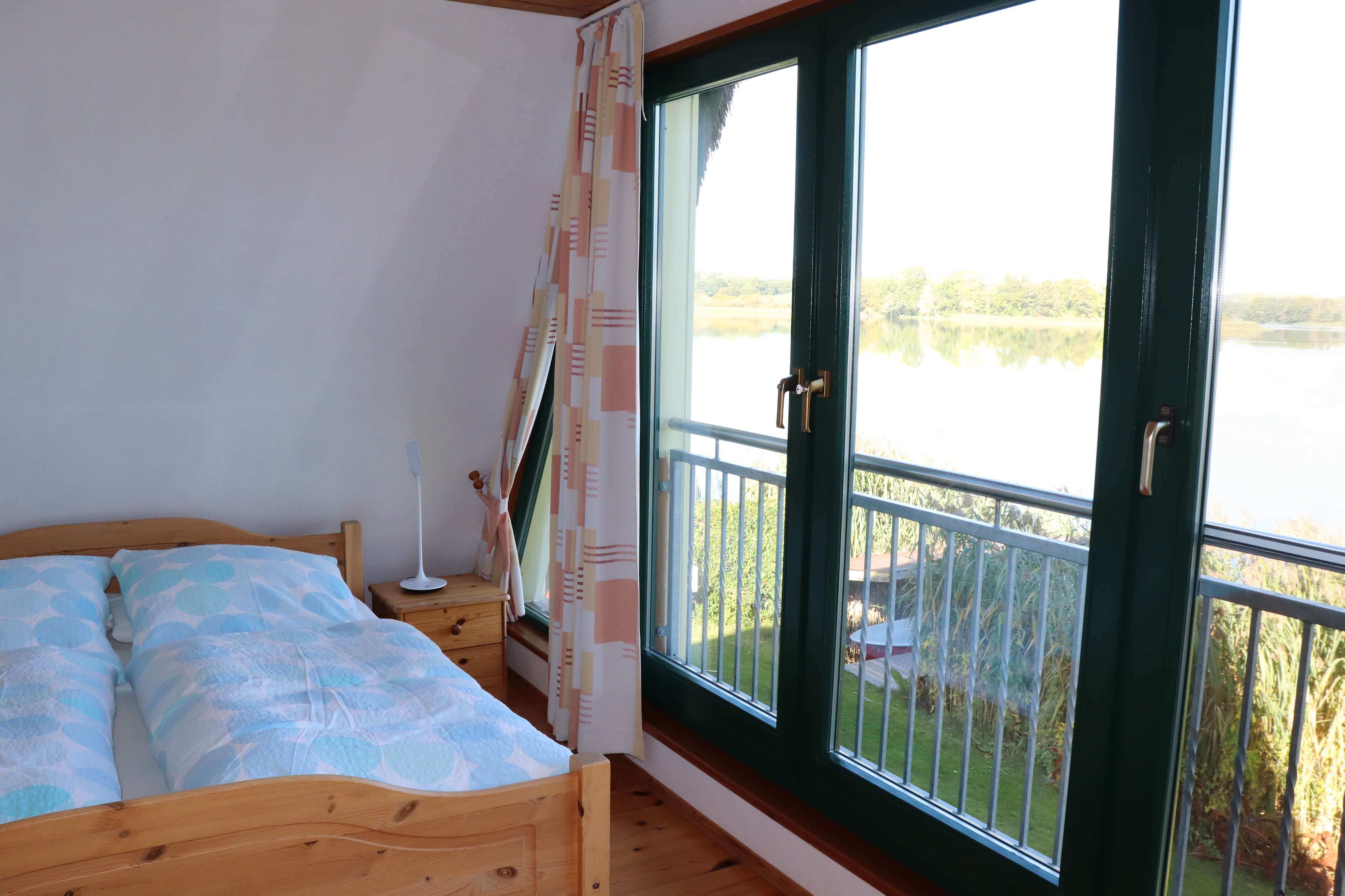 Schalfzimmer mit einem Doppelbett und Ausblick auf den Sternberger See.