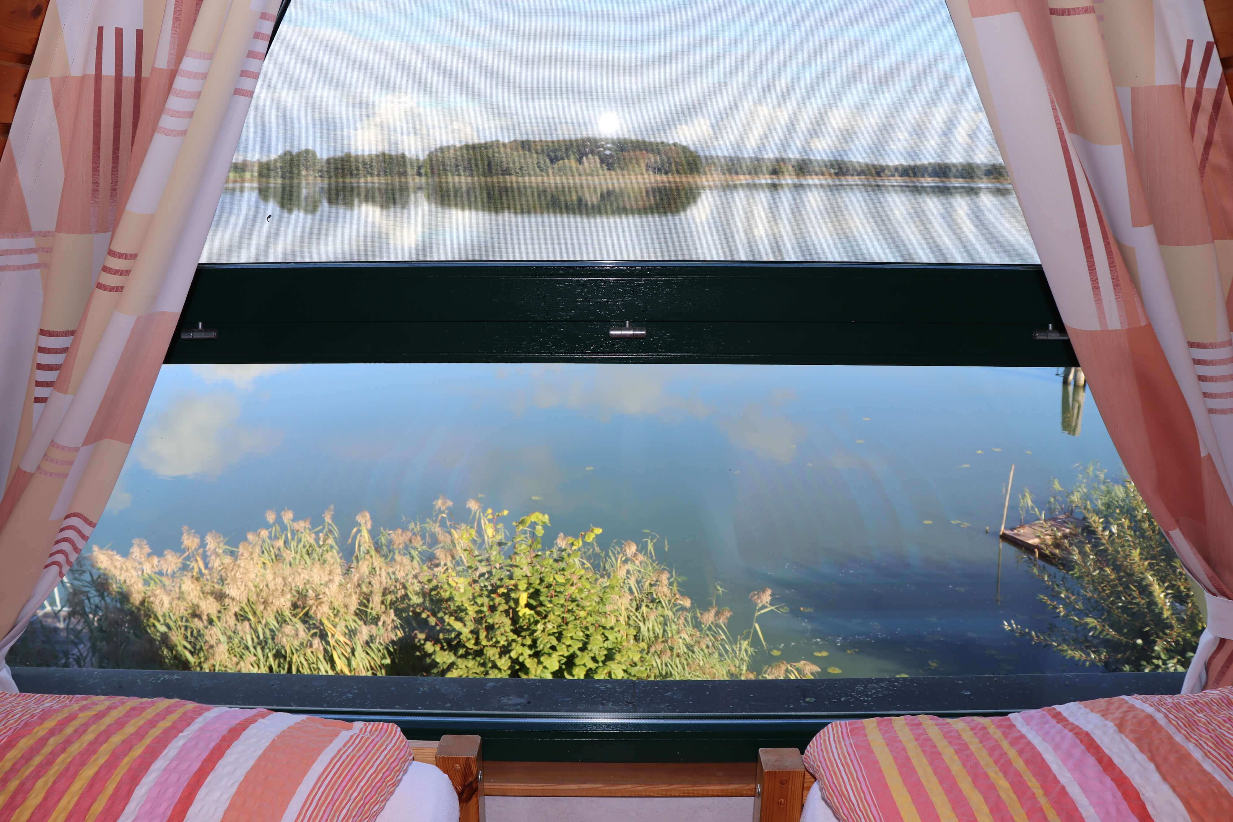 Schlafzimmer mit zwei getrennten Betten und einem Holzschrank für jeweils einen Feriengast und wundervollem Ausblick auf den Sternberger See