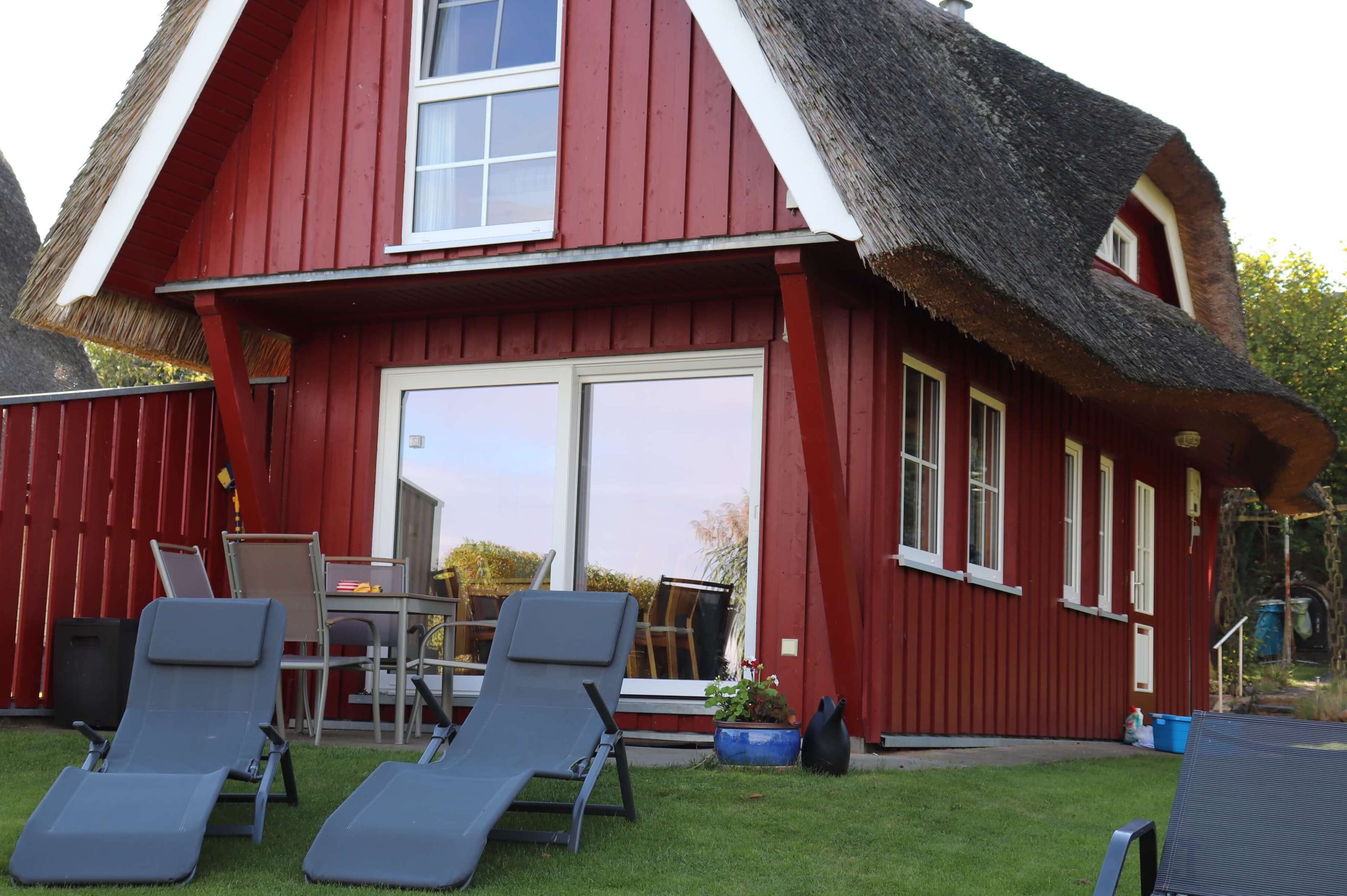 Kleines Ferienhaus der Familie Ohde am Sternberger See mit einer gelben Holzfassade, einem Reetdach und einer kleinen Terrasse.
