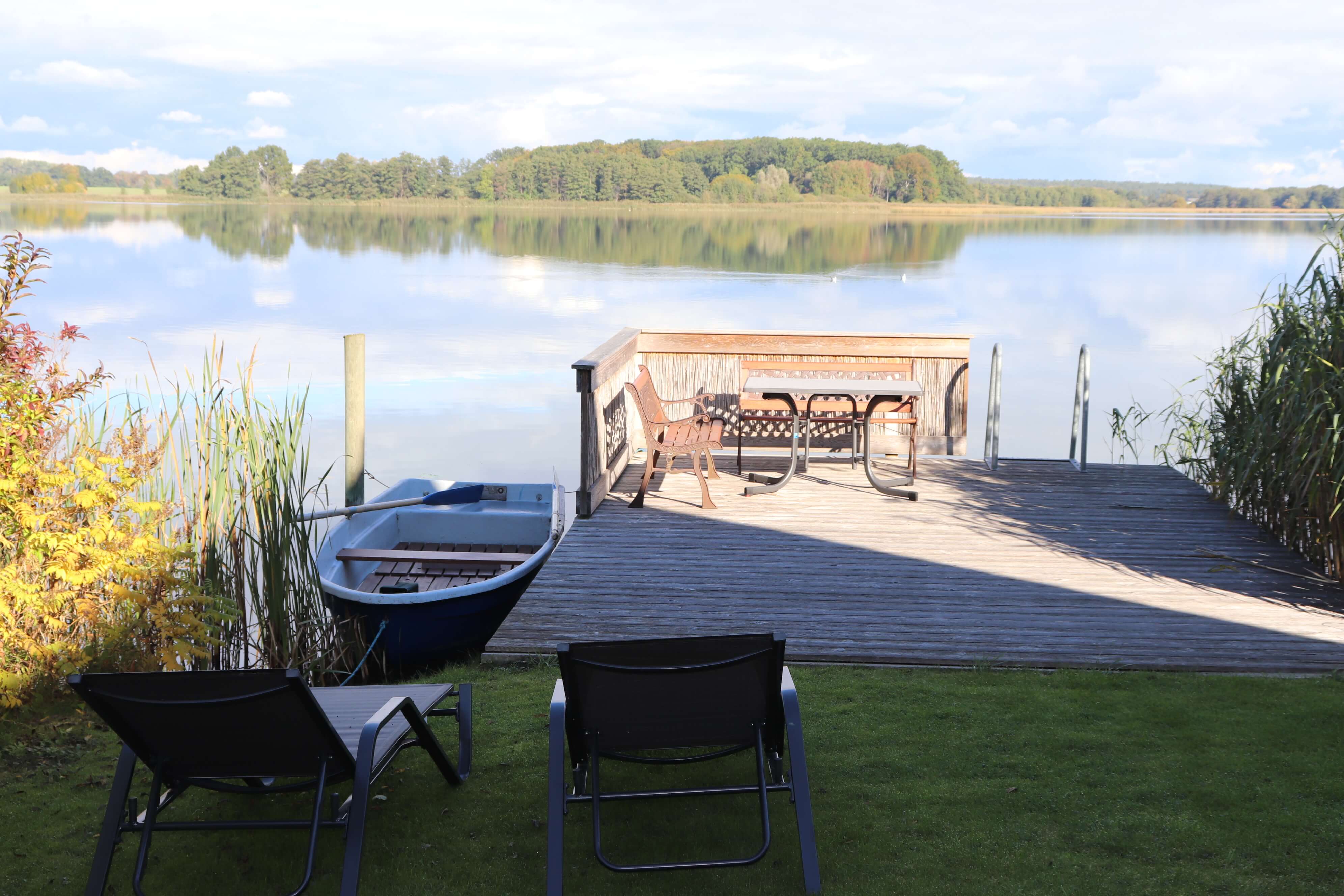 Blick auf die idyllische Wasserterrasse auf dem Sternberger See mit zwei Stühlen und einem Tisch.