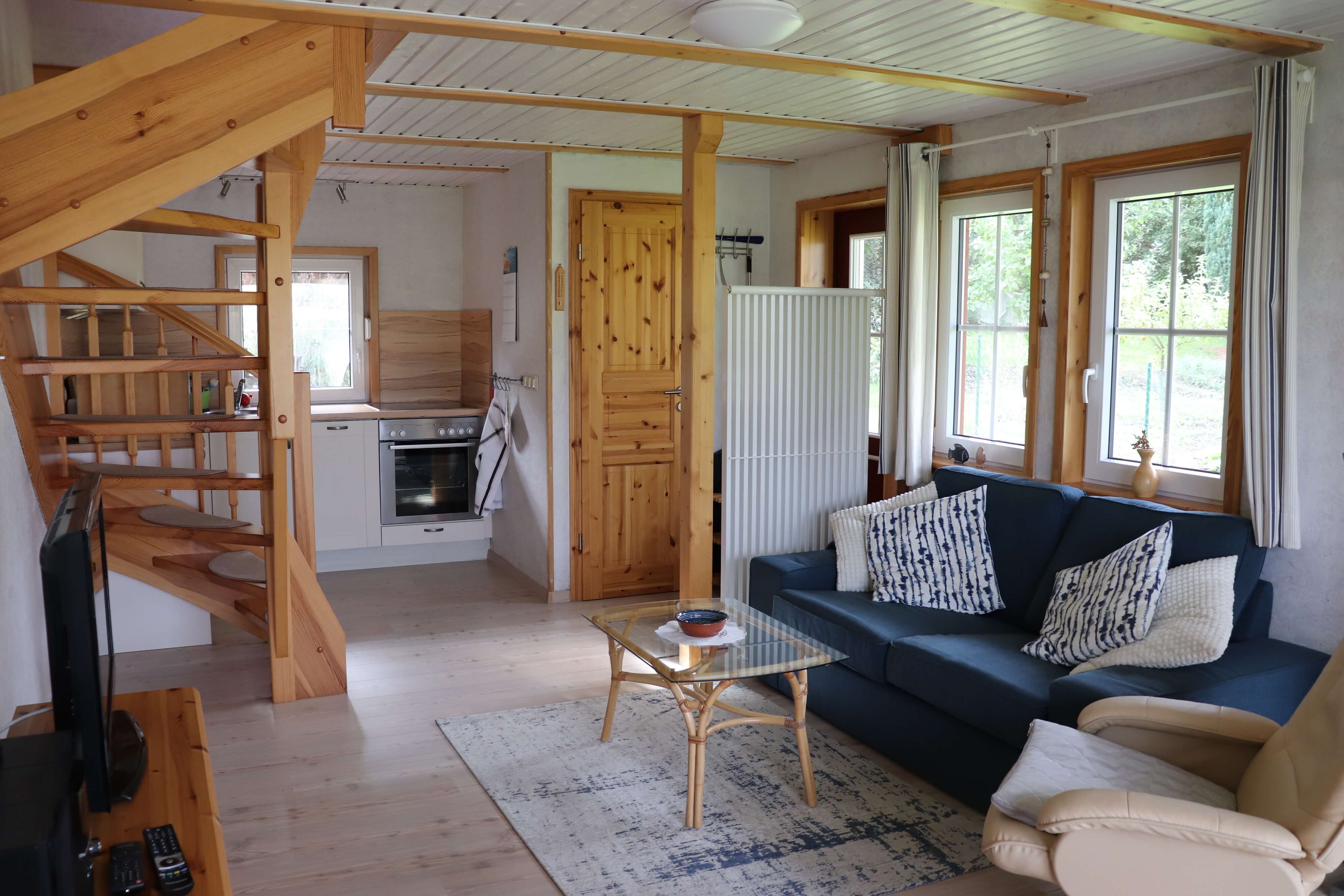 Blick auf eine blaue Couch und einem Holztisch im Inneren des kleinen Ferienhauses der Familie Ohde.