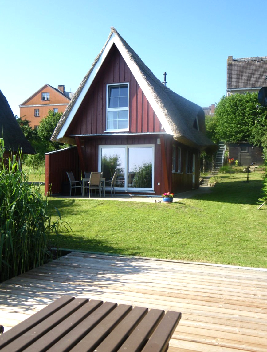 Kleines Ferienhaus der Familie Ohde am Sternberger See mit einer gelben Holzfassade, einem Reetdach und einer kleinen Terrasse.