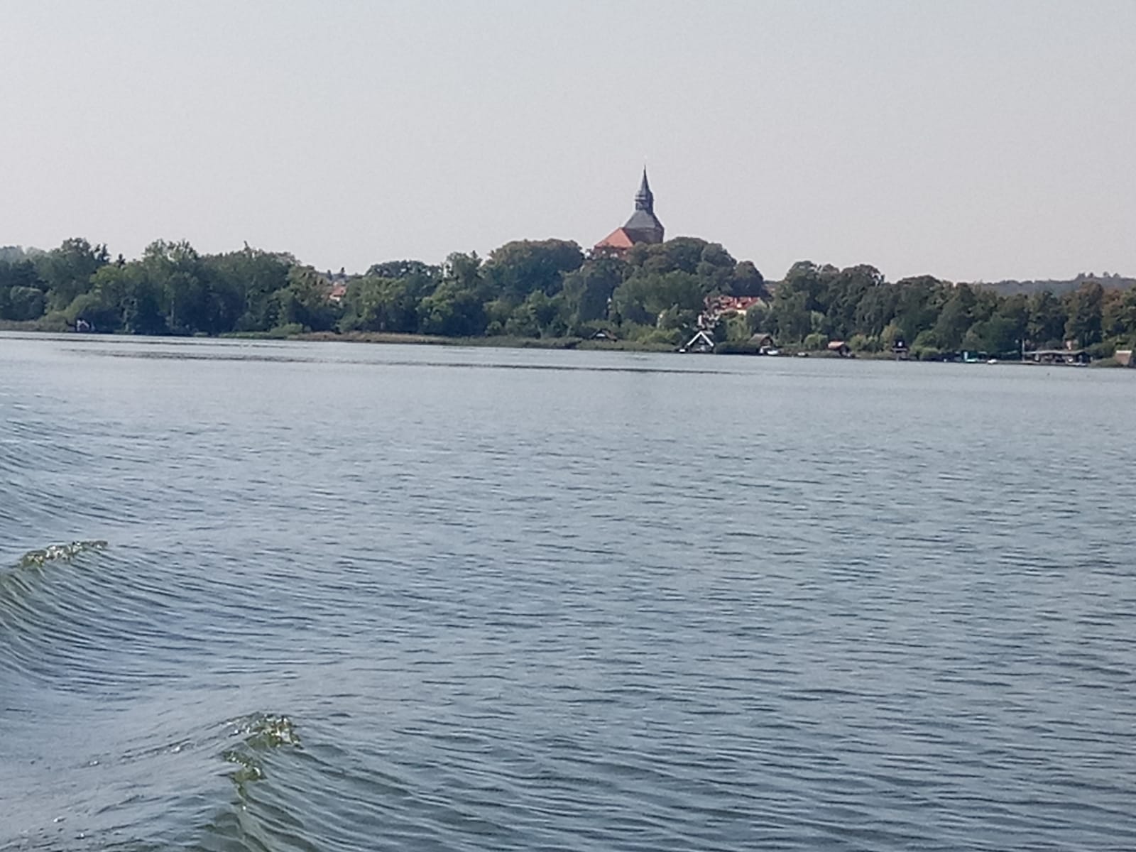 Im Vordergrund der Sternberger See mit der Silhouette der Stadt im Hintergrund.