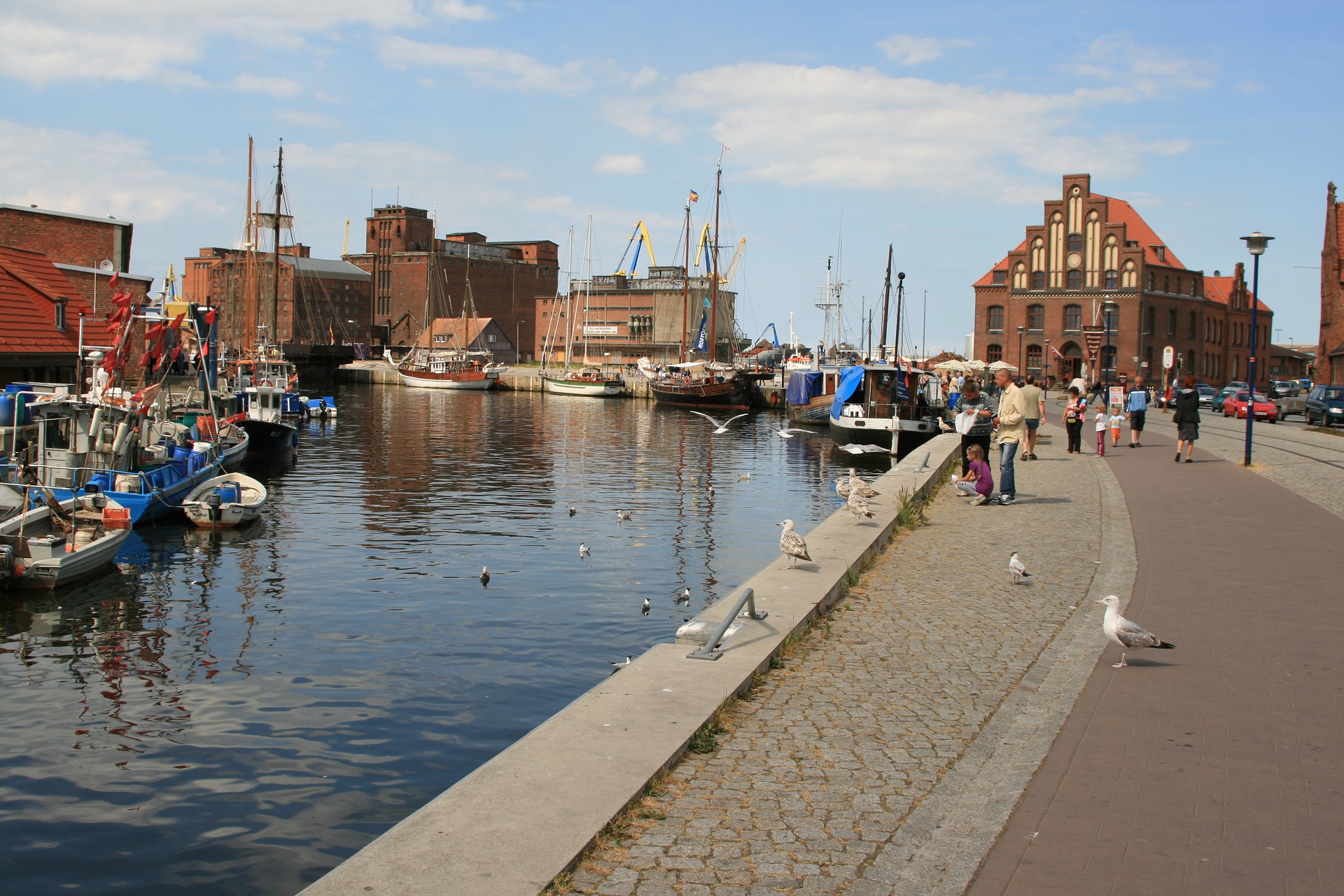 Blick auf den Hafen von Wismar mit mehreren Booten im Vordergrund und rotbraunen Backsteinhäusern im Hintergrund